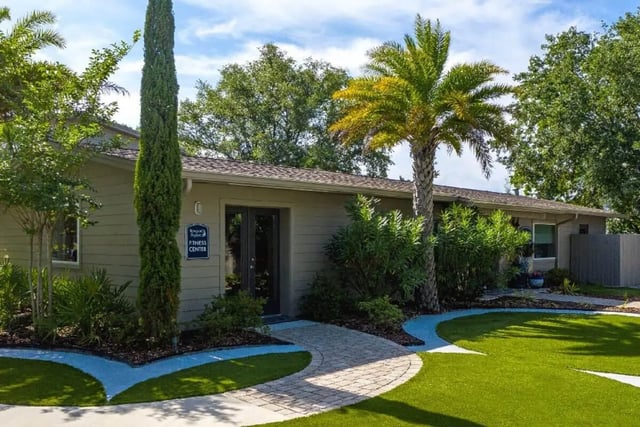 Fitness center entrance with palm trees and landscaping exterior at Newport Square Apartments in Colorado Springs Student Accommodation