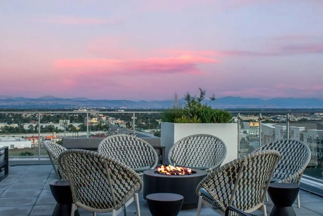 Wicker chairs surround fire pit with city view exterior at RYE SoBo in Denver Student Accommodation