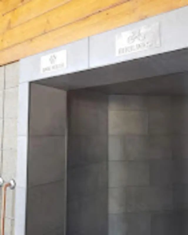 Two signs above grey tiled entrance exterior at The House Apartments in Eagle Student Accommodation