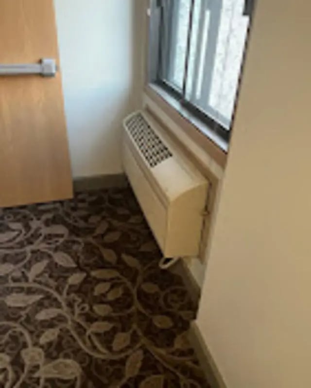 Air conditioner window and floral carpet room at The House Apartments in Eagle Student Accommodation