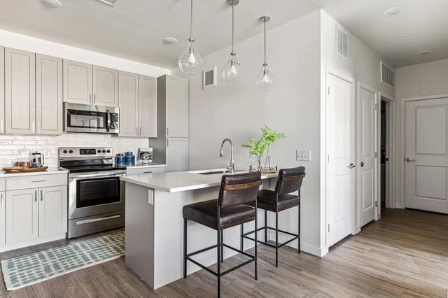 Gray cabinets oven microwave sink island bar stools kitchen at Vida @ Fitzsimons in Aurora Student Accommodation
