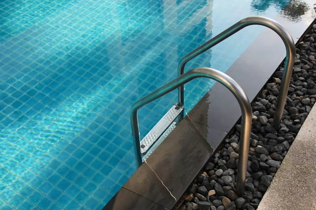 Pool ladder with metal handrails and blue tiled water Pool at Vida @ Fitzsimons in Aurora Student Accommodation