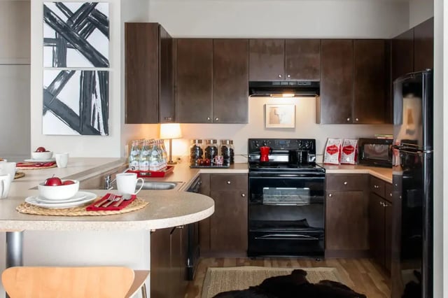 Kitchen counter with dishes, oven, cabinets, and art at Campus Quarters at Corpus Christi in Corpus Christi Student Accommodation