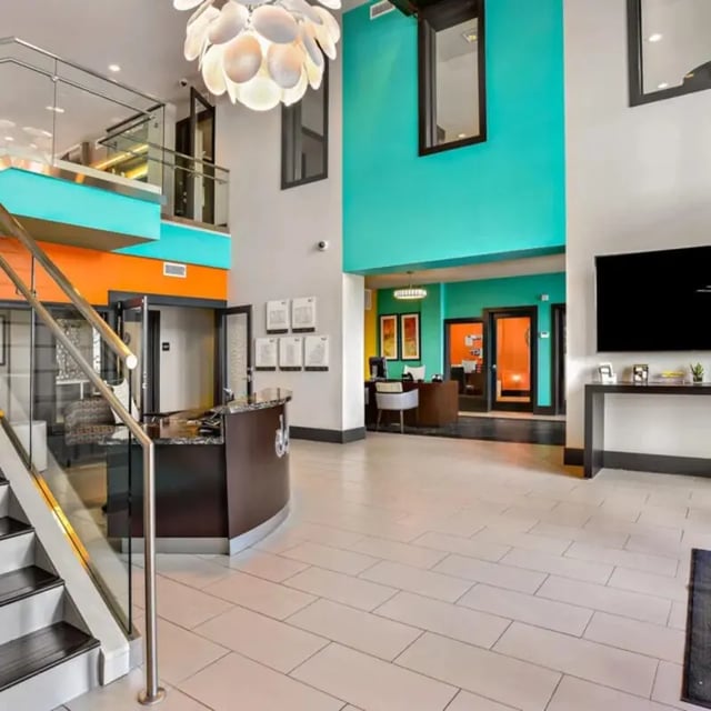 Reception desk with stairs and teal wall lobby area at The Den in Columbia Student Accommodation