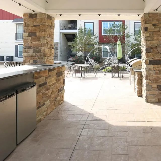 Outdoor kitchen with tables chairs and hammocks exterior at The Den in Columbia Student Accommodation