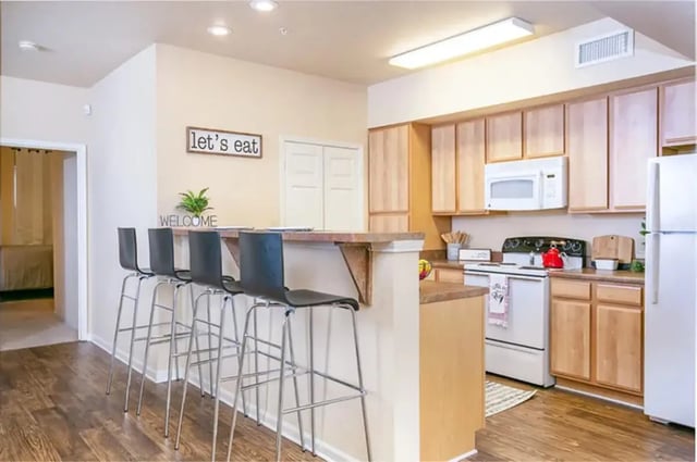 Bar stools welcome sign kitchen cabinets and appliances kitchen at University Crossing Apartments Ruston in Ruston Student Accommodation