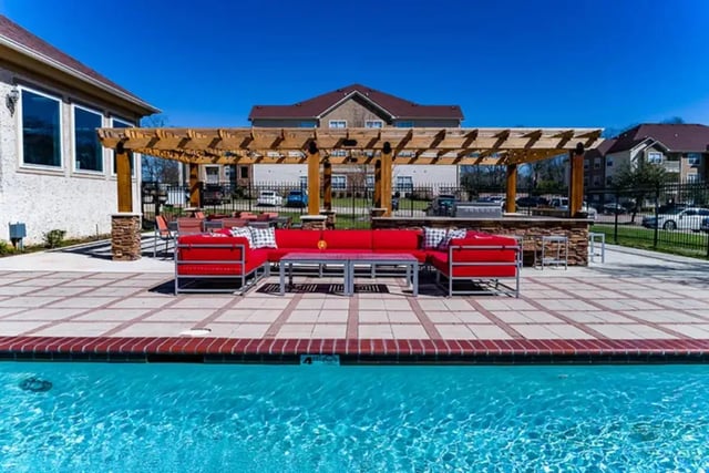 Red lounge seating under pergola by pool exterior at University Crossing Apartments Ruston in Ruston Student Accommodation