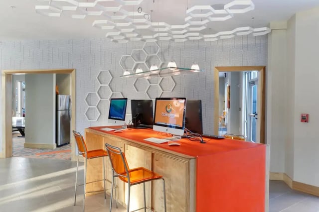 Computers and orange chairs common area at The Dillon Bloomington in Bloomington Student Accommodation