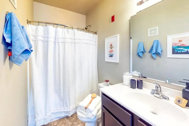 Toilet with towels shower curtain and sink bathroom at The Dillon Bloomington in Bloomington Student Accommodation