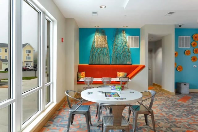 White table chairs orange bench board games common area at The Dillon Bloomington in Bloomington Student Accommodation