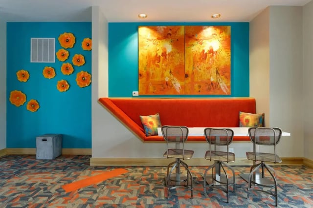 Orange banquette abstract art and stools lounge area at The Dillon Bloomington in Bloomington Student Accommodation