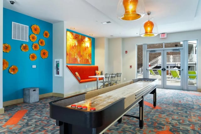 Shuffleboard table orange seating abstract art common area at The Dillon Bloomington in Bloomington Student Accommodation