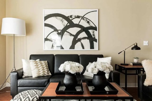 Black sofa framed artwork white roses coffee table living room at University Village at Greensboro in Greensboro Student Accommodation