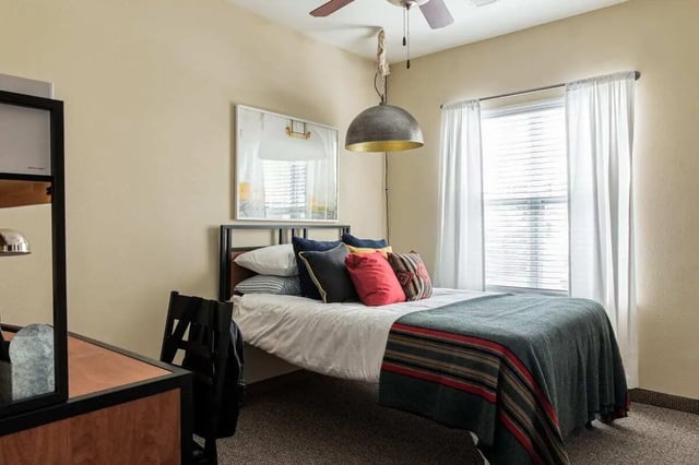 Bed with pillows desk chair and window bedroom at University Village at Greensboro in Greensboro Student Accommodation