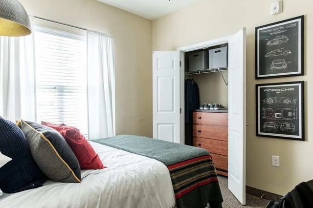 Bed with pillows closet with dresser and Porsche art Bedroom at University Village at Greensboro in Greensboro Student Accommodation