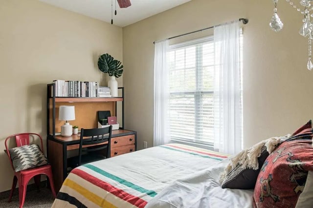 Bed with striped blanket desk and chair Bedroom at University Village at Greensboro in Greensboro Student Accommodation