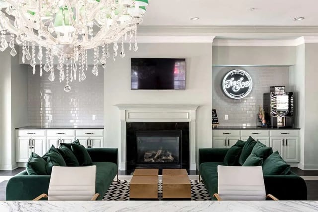 Dark green sofas fireplace TV coffee bar area living room at University Village at Greensboro in Greensboro Student Accommodation