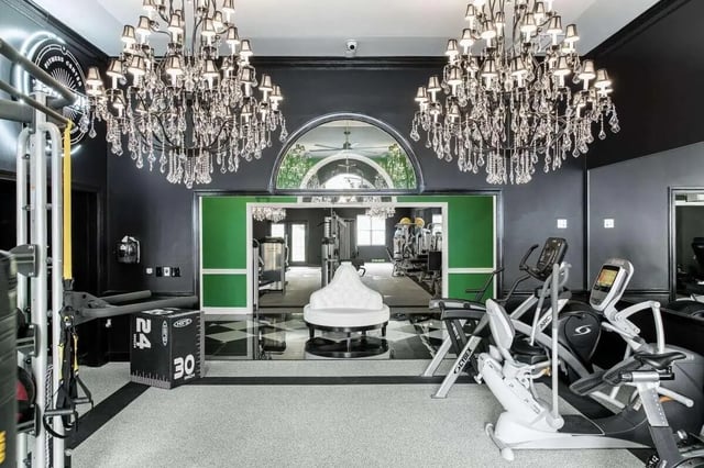 Gym equipment chandeliers mirrored arch white seating fitness area at University Village at Greensboro in Greensboro Student Accommodation