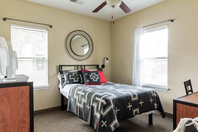 Bed with patterned blanket mirror and nightstand bedroom at University Village at Greensboro in Greensboro Student Accommodation
