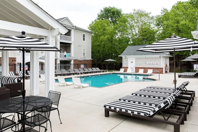 Pool lounge chairs umbrellas and tables exterior at University Village at Greensboro in Greensboro Student Accommodation