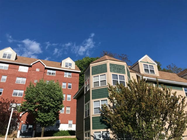 Brick and tan buildings with green accents exterior at Auden Ithaca in Ithaca Student Accommodation