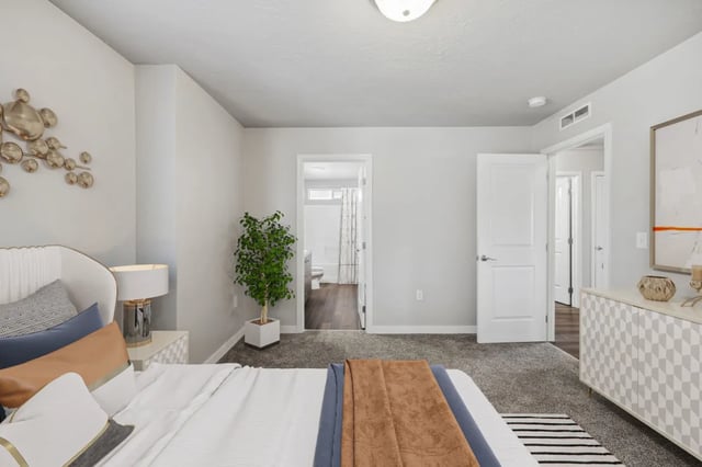 Bed with pillows plant dresser and bathroom bedroom at Ridgecrest Commons in Nampa Student Accommodation