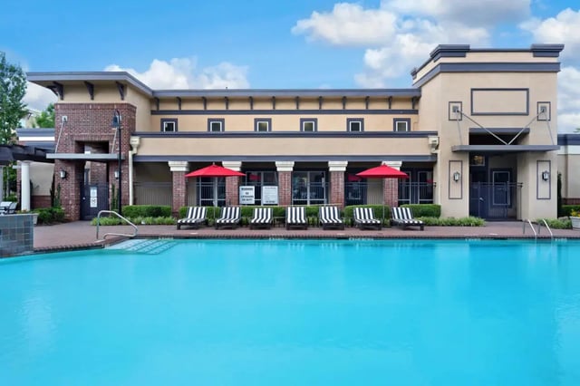 Pool with lounge chairs and red umbrellas exterior at The Crimson in Tuscaloosa Student Accommodation