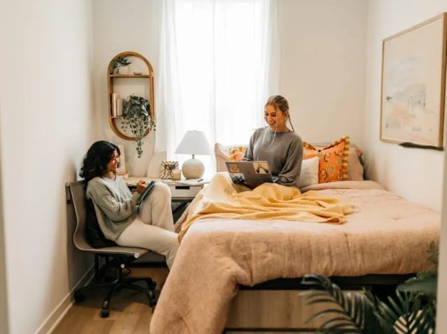 Two students studying at desks in a bedroom. at Rambler Athens in Atlanta Student Accommodation