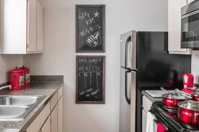 Kitchen with double sink fridge and stovetop kitchen at The London in College Station Student Accommodation