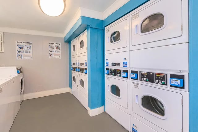 Stacking washers and dryers with instructional posters laundry area at Belmont Crossing in Smyrna Student Accommodation