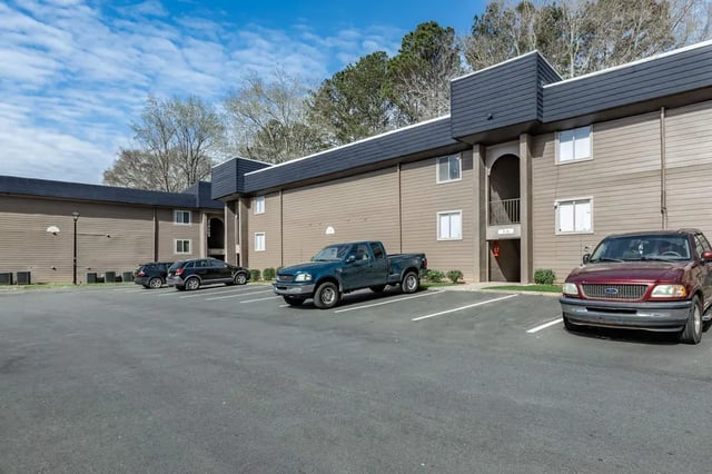 Apartment building with parking lot and cars exterior at Villas De Las Colinas 1 in Atlanta Student Accommodation