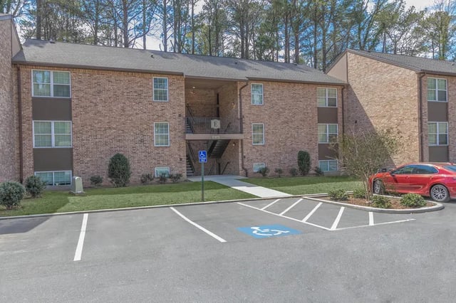 Brick apartment building with parking and landscaping exterior at Villas De Las Colinas 2 in Atlanta Student Accommodation