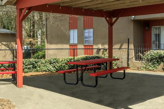 Red picnic table under covered patio outdoor area at Villas De Las Colinas 3 in Atlanta Student Accommodation