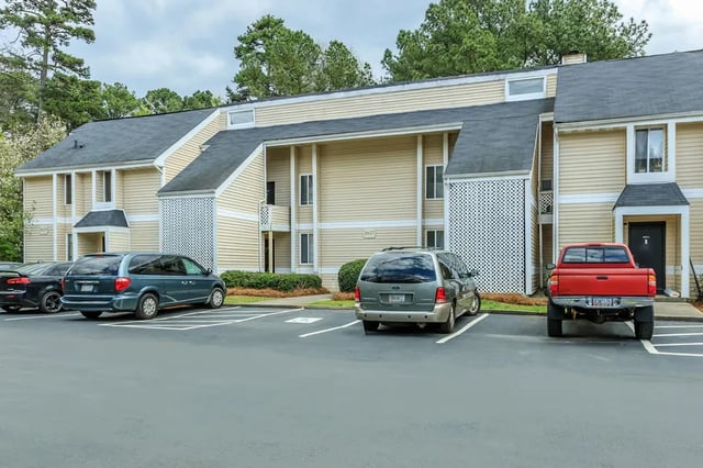 Tan apartment buildings with cars parked exterior at Villas De Las Colinas 4 in Atlanta Student Accommodation