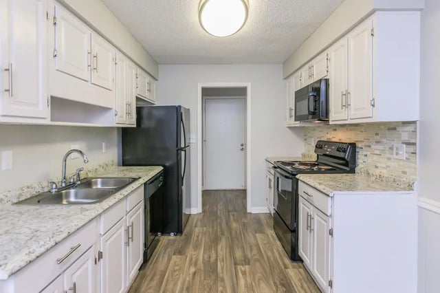 Kitchen with white cabinets black appliances and granite countertops kitchen at Villas De Solana in Atlanta Student Accommodation