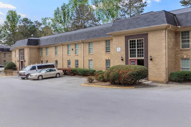Brick apartment building with parking cars exterior at Villas De Solana in Atlanta Student Accommodation