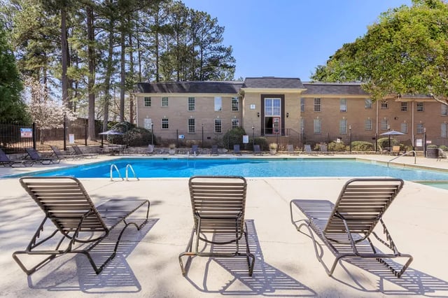 Lounge chairs by a bright blue pool exterior at Villas De Solana in Atlanta Student Accommodation