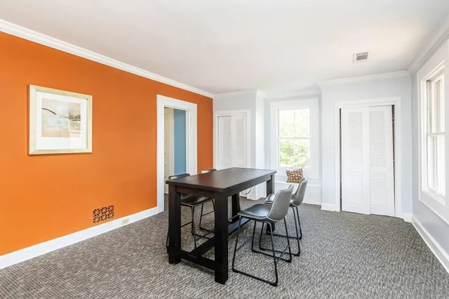 Tall dark table four chairs artwork orange wall dining area at Villas Del Mirasol in Roswell Student Accommodation