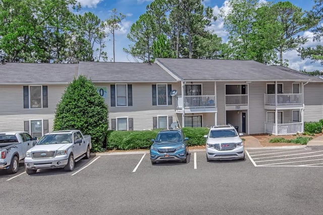 Apartment building with vehicles in parking lot exterior at Villas Del Mirasol in Roswell Student Accommodation