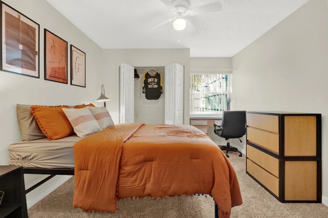 Orange duvet bedding, desk, dresser, closet bedroom at on50 Tampa Apartments in Tampa Student Accommodation