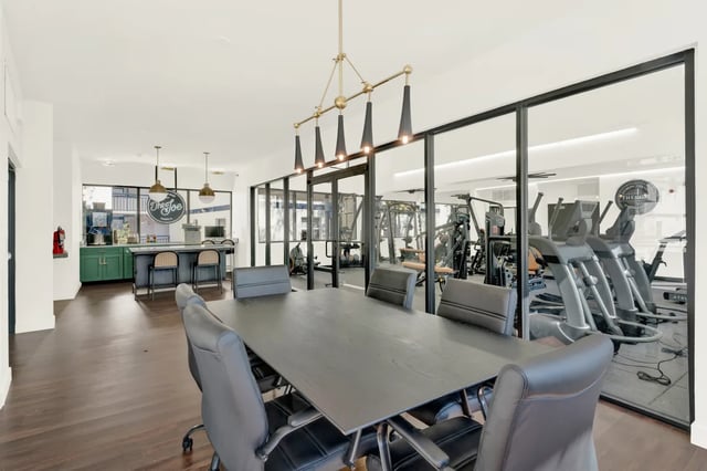 Meeting table with chairs and gym visible through glass at on50 Tampa Apartments in Tampa Student Accommodation