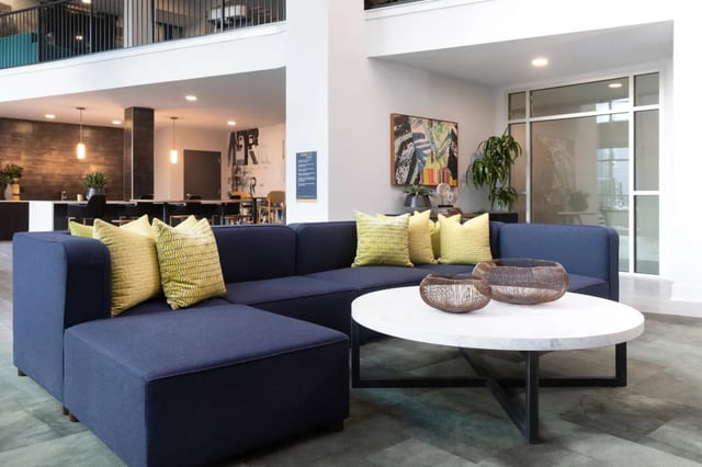 Blue sectional sofa yellow patterned pillows white coffee table living room at The Indy Apartments in Marietta Student Accommodation