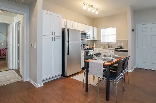Dining table and chairs with kitchen view kitchen at The Leonard Denton in Denton Student Accommodation