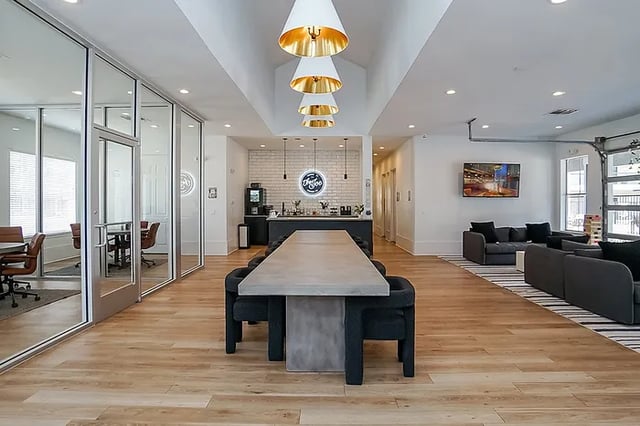 Long table with chairs and lounge seating living room at The Leonard Denton in Denton Student Accommodation