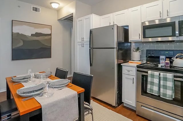Dining table with place settings and kitchen area at The Leonard Denton in Denton Student Accommodation
