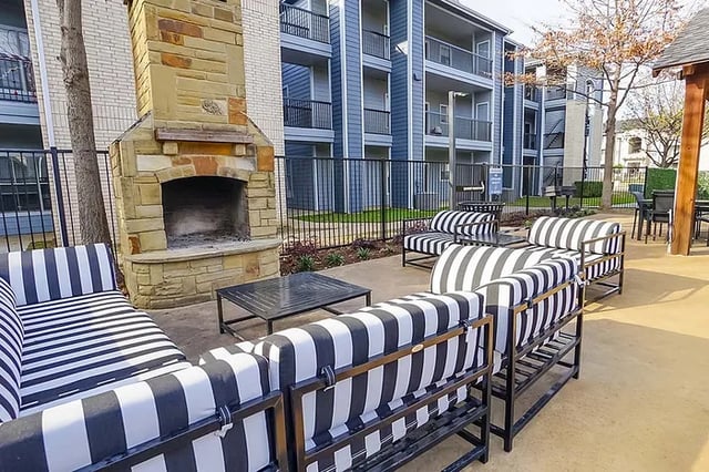 Outdoor fireplace striped couches patio tables living area at The Leonard Denton in Denton Student Accommodation