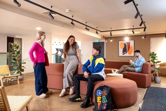 Students talking on sectional sofa modern living room at Stapleton House in London Student Accommodation