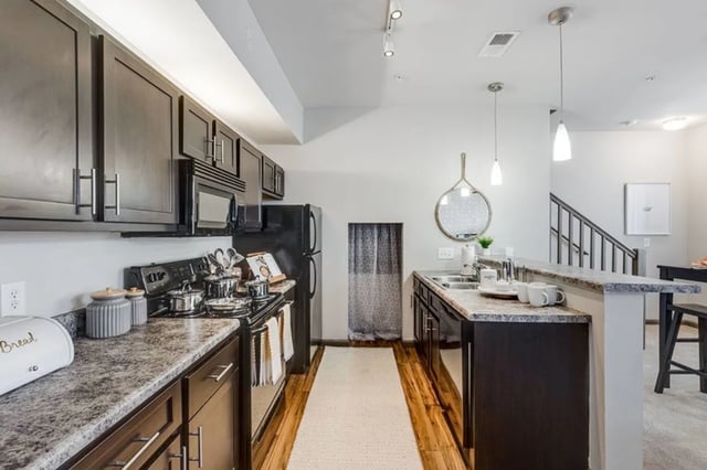 Dark cabinets microwave stove refrigerator kitchen at The James Apartments Richmond in Richmond Student Accommodation