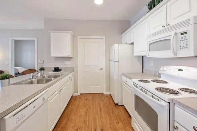 White cabinets double sink stove microwave refrigerator kitchen at University Edge-Cincinnati in Cincinnati Student Accommodation