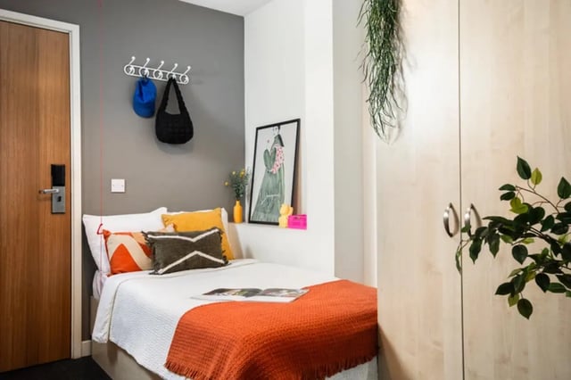 Bed with orange blanket and pillows bedroom at Quantum Court in London Student Accommodation
